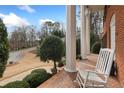 Charming front porch with white columns, brick flooring, and a cozy rocking chair to enjoy the view at 1380 Tennis Court Pl, Roswell, GA 30075