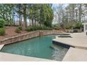 Backyard pool featuring stone accents, lush landscaping, and outdoor seating area at 1380 Tennis Court Pl, Roswell, GA 30075