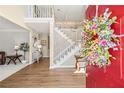 Inviting foyer with wood floors, staircase, and a bright red door adorned with a floral wreath at 5945 Masters Club Dr, Suwanee, GA 30024