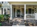 Inviting front porch featuring classic columns, brick steps, and stylish hanging lanterns at 1416 Elgin Way, Cumming, GA 30041