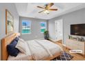 Staged main bedroom with tray ceiling, wood floors, ensuite bathroom, and bright double windows at 1681 Graystone Dr, Hampton, GA 30228