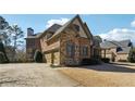 Side view of home featuring a brick and stone facade, a three-car garage and a well-maintained lawn at 2916 Kings Walk Ave, Marietta, GA 30062