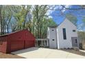 Striking exterior showcasing modern design, a red detached two-car garage, and a walkway to the house in a wooded setting at 145 Cedarwood Ln, Roswell, GA 30075