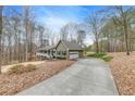 View of the home featuring attached garage, long driveway and natural surroundings at 1980 Two Springs Way, Lawrenceville, GA 30043