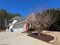 View of the side of this home featuring an attached garage and brick accents at 3650 Burnt Hickory Dr, Dacula, GA 30019