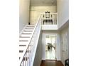 Bright foyer with hardwood floors, white staircase, and view into a dining room with a ceiling fan at 929 Bexhill Dr, Lawrenceville, GA 30043