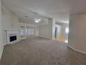 Open living room with a fireplace and large windows, seamlessly connecting to the dining area with hardwood floors at 983 Noble Oak Ct, Lawrenceville, GA 30046