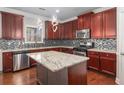 Modern kitchen with cherry wood cabinets, granite countertops, stainless steel appliances and kitchen island at 4525 Hopewell Manor Dr, Cumming, GA 30028