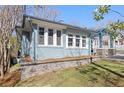 Side angle view of a blue brick house with a stone retaining wall and pergola-covered front porch at 28 Peachtree Hills Ne Ave, Atlanta, GA 30305