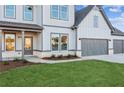 Home featuring a manicured lawn and a three-car garage, grey and white siding, and covered porch at 2759 Porches Ln, Dacula, GA 30019