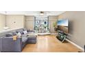 Living room features a comfortable sectional sofa, large windows, hardwood flooring, and a ceiling fan at 8740 Jenkins Rd, Winston, GA 30187