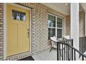 Inviting front porch with a yellow door, brick facade, and seating area at 135 Eastmark Way, Fayetteville, GA 30214
