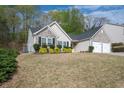 An exterior view of a single-Gathering home featuring a 2-car garage and mature trees surrounding the property at 1851 Millwood Park Ct, Buford, GA 30518