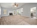 Spacious living room with fireplace, plush carpet, ceiling fan, and view of the open kitchen at 1851 Millwood Park Ct, Buford, GA 30518