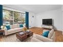 Bright living room with hardwood floors, large window with curtains, modern furniture, and white walls at 5726 Southwick Sw Ct, College Park, GA 30349