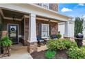 Inviting front porch with stone columns and seating area with decorative plants and water feature at 108 Summer Breeze Ln, Canton, GA 30114
