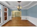 Elegant dining room with hardwood floors, wainscoting, and a decorative chandelier at 10890 Regal Forest Dr, Suwanee, GA 30024