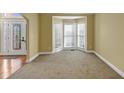 Bright living room featuring a large bay window, neutral carpet, and white trim throughout at 10890 Regal Forest Dr, Suwanee, GA 30024