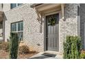 Welcoming gray front door of a light brick townhome, complete with a wreath and manicured bushes at 4358 White Spruce Aly, Doraville, GA 30360