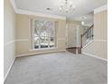 Bright living room with large window, neutral walls, and staircase; perfect for entertaining or relaxing at 1056 Shadow Lake Dr, Lithonia, GA 30058