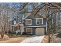 Charming two-story home with blue siding, white trim, and an attached garage against a wooded backdrop at 2111 Glenwood Downs Dr, Decatur, GA 30035