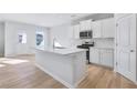 Modern kitchen with white cabinets, a large island with breakfast bar, and stainless steel appliances at 517 Elkwood Ln, Mcdonough, GA 30253