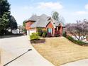 Exterior view of a stately two-story home showcasing lush landscaping and a circular driveway leading to a two-car garage at 1574 Stepstone Way, Lawrenceville, GA 30043