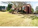 Exterior angle view of a red brick home with lush green lawn and tasteful landscaping in a suburban neighborhood at 1574 Stepstone Way, Lawrenceville, GA 30043