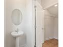 Half bathroom featuring a pedestal sink, an oval mirror, and wood-look floors at 982 Sutherland Ln (Lot 30), Lawrenceville, GA 30043