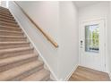 Inviting entryway featuring a carpeted staircase with a wooden handrail and a white front door with glass panes at 984 Sutherland Ln (Lot 31), Lawrenceville, GA 30043