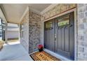 Stylish home entrance with a modern, gray double door, brick facade, and a 'Welcome' mat at 4015 Sierra Vista Cir, Cumming, GA 30028