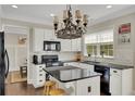 Kitchen with black appliances, dark countertops, white cabinets, and a center island at 690 Floral Pl, Suwanee, GA 30024