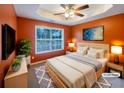 Staged main bedroom featuring a tray ceiling, ceiling fan, large window and two wall-mounted TVs at 175 Stillwood Dr, Fayetteville, GA 30215