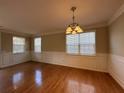 Bright dining room with hardwood floors, decorative molding, a modern chandelier, and large windows at 4310 Alysheba Dr, Fairburn, GA 30213