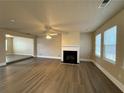 Spacious living room with hardwood floors, a cozy fireplace, a ceiling fan, and natural light from windows at 5488 Wexford Pass, Atlanta, GA 30349