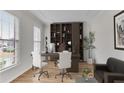 This office features neutral paint, shelving and storage solutions, two windows and two white office chairs at 1900 Sanborne Way, Dacula, GA 30019