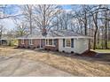 Side view of a brick home with a dark roof and mature trees, situated on a sloped lawn at 35 Adair Dr, Marietta, GA 30066