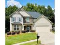 Beautiful home with a lush green lawn, mature trees, and an inviting driveway leading to the garage at 4357 Kershaw Dr, Snellville, GA 30039