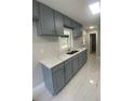 Modern kitchen featuring gray cabinets, marble countertops, and stainless steel sink at 1808 Brewer Sw Blvd, Atlanta, GA 30310