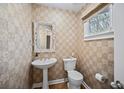 Stylish powder room featuring a pedestal sink, patterned wallpaper, and a window at 8540 Hope Mews Ct, Atlanta, GA 30350