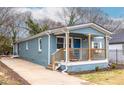 Single story blue home featuring a long driveway and covered front porch with rocking chairs at 75 Mayson Ne Ave, Atlanta, GA 30307