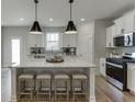 Bright kitchen featuring a large island with seating, sleek stainless appliances and modern pendant lights at 1238 Ainsworth Aly # 38, Sugar Hill, GA 30518