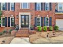 Inviting brick home entrance with black door, tidy landscaping, and classic architectural details at 10815 Donamere Dr, Johns Creek, GA 30022