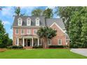 Charming two-story brick home with a manicured lawn, black door, and a welcoming front porch at 4992 Price Dr, Suwanee, GA 30024