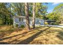 Single-story home with carport surrounded by mature trees and lush landscaping at 1652 Pine Cir, Austell, GA 30168
