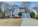 Inviting blue two-story home featuring a well-maintained front yard and attached two car garage at 2382 Merrymount Dr, Suwanee, GA 30024