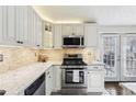 Bright kitchen with stainless steel appliances, gas range, white cabinets, granite countertops and french doors to the outside at 10475 Willow Meadow Cir, Alpharetta, GA 30022