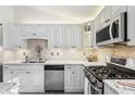 Well-equipped kitchen with stainless steel appliances, stylish cabinetry, tile backsplash, and sleek granite countertops at 10475 Willow Meadow Cir, Alpharetta, GA 30022