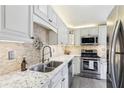 Modern kitchen featuring white cabinetry, stainless steel appliances, granite countertops and a tiled backsplash at 10475 Willow Meadow Cir, Alpharetta, GA 30022