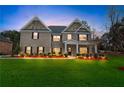 Two-story home at dusk, with green lawn, landscape lighting, and manicured bushes at 3759 Chapel Cv, Douglasville, GA 30135